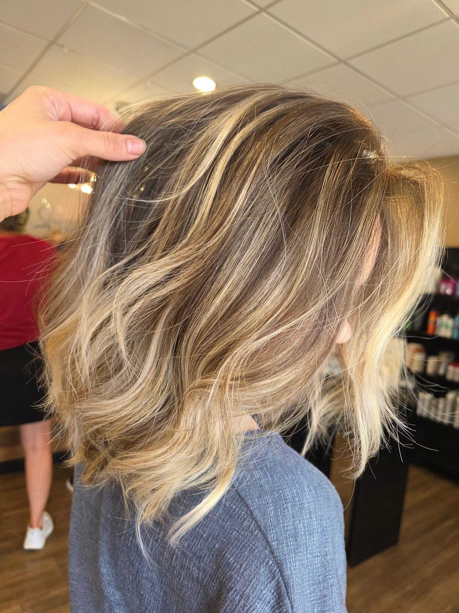 Wavy blonde balayage hairstyle in a salon setting.